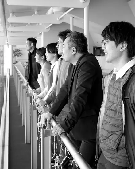 窓辺の手すりに並び、街を見下ろすメンバー
