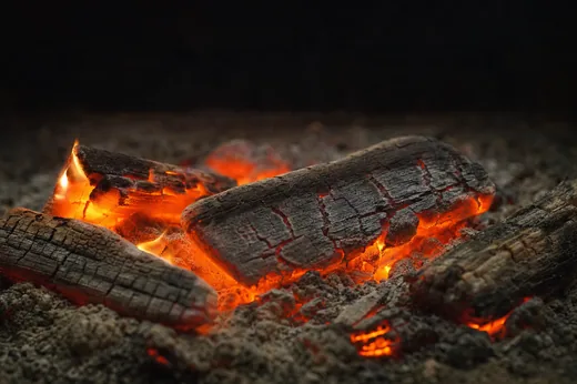 灰の上に残った薪が、割れ目からオレンジ色に燃えている熾火